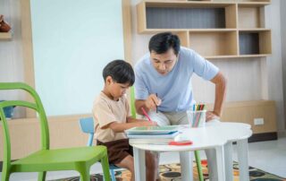 Child receiving learning support at a table with adult guidance, reflecting focus and task practice similar to occupational therapy sessions in Phnom Penh.