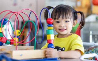 Young girl at preschool engaging in fine motor activities with colorful educational toys
