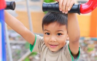 A smiling child building physical strength and coordination through playful activities, highlighting the benefits of occupational therapy in Phnom Penh.