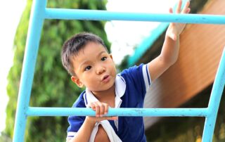 Child climbing play equipment outdoors during a motor-focused occupational therapy session in Phnom Penh, supporting coordination and confidence.