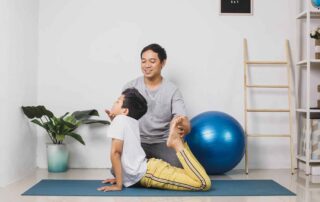 A child practicing flexibility and body awareness exercises during occupational therapy with an instructor at OrbRom Center in Phnom Penh.