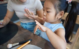 A young girl practicing fine motor skills at a table with her mother during an occupational therapy-inspired activity at OrbRom Center Phnom Penh.