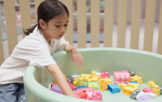 A young child working on fine motor skills by playing with colorful building blocks, part of an occupational therapy activity in Phnom Penh.