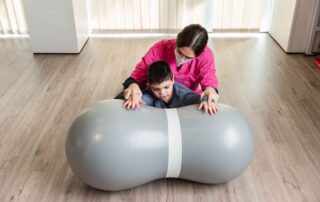 Child working with an occupational therapist on a peanut ball to improve core strength and motor planning in Phnom Penh