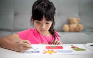 Child focused on painting during a fine motor and attention-building occupational therapy activity in Phnom Penh.