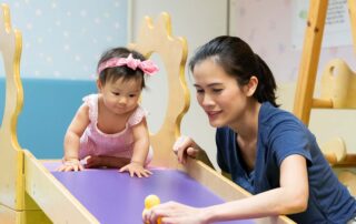 A therapist in Phnom Penh supports a baby during occupational therapy by engaging in a toy-following activity to promote motor and visual development.