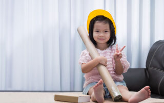 A child engaging in imaginative play while holding a cardboard tube, demonstrating fine motor and pretend play skills encouraged in occupational therapy.