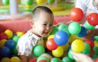 Child enjoying colorful sensory play in a ball pit, a common tool used in occupational therapy in Phnom Penh to support sensory and motor development.