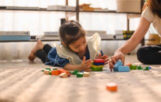 Child engaging in floor-based block play during occupational therapy to build fine motor and cognitive skills in Phnom Penh.