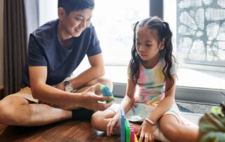 A child and caregiver working on fine motor skills development through playful occupational therapy activities in Phnom Penh.