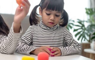 Child developing hand strength and fine motor skills through play-based occupational therapy activities at OrbRom Center Phnom Penh