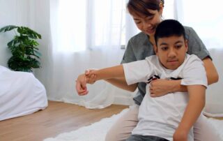Occupational therapist supporting a child through stretching and mobility exercises to improve daily function and flexibility in Phnom Penh