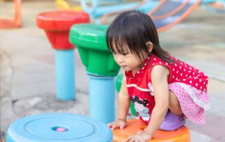 Toddler girl engaged in outdoor climbing play during a gross motor-focused occupational therapy activity in Phnom Penh.