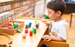A young child in Phnom Penh explores colorful sensory toys during an occupational therapy session at OrbRom Center.