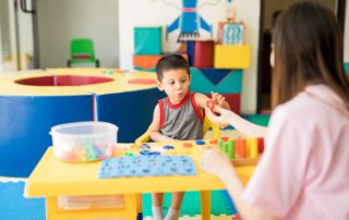 A young boy practices fine motor skills with the help of a therapist during an occupational therapy session in Phnom Penh.