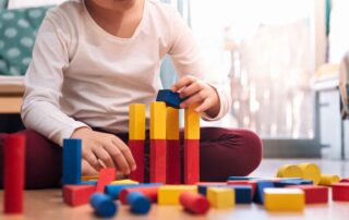 A child stacks colorful wooden blocks during an occupational therapy session focused on fine motor and problem-solving skills in Phnom Penh.