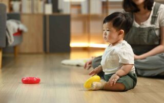 Toddler exploring sensory toys during early occupational therapy at home with parental support in Phnom Penh.