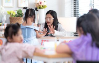 A teacher or therapist engaging with a young student using hand activities in a classroom setting, supporting learning through occupational therapy.