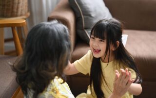 Young girl smiling and engaging in playful interaction with a family member, showing progress in social bonding through therapy.