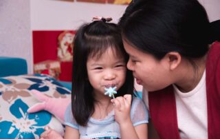 A young girl smiles while interacting closely with a caregiver, showing emotional connection and comfort during play.