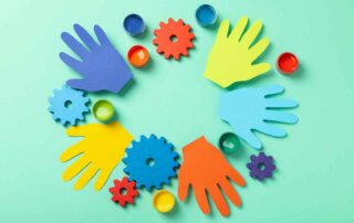 Colorful cut-out paper hands and gears representing fine motor skill activities and occupational therapy for children at OrbRom Center in Phnom Penh.