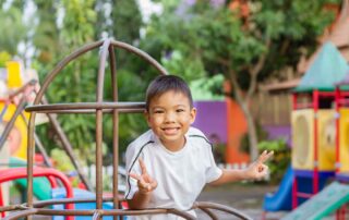 Smiling boy playing on climbing equipment during an occupational therapy session in Phnom Penh