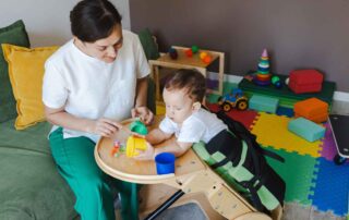A therapist working with a toddler in a supportive therapy chair during an early intervention occupational therapy session in Phnom Penh