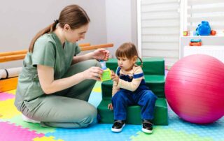Occupational therapist engaging a toddler in a play-based fine motor activity on soft blocks at OrbRom Center Phnom Penh