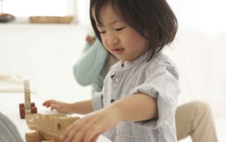 Child developing fine motor skills during an occupational therapy session with wooden toys in Phnom Penh