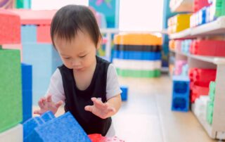 Toddler exploring large colorful blocks during occupational therapy activity at OrbRom Center Phnom Penh
