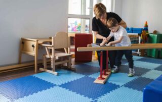 A child with cerebral palsy working on mobility skills with a therapist using adaptive equipment at OrbRom Center in Phnom Penh