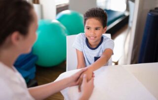 A young boy working on hand strength exercises with a therapist during pediatric occupational therapy in Phnom Penh