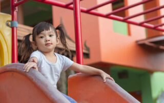 Child at the top of a playground slide during an occupational therapy activity session in Phnom Penh