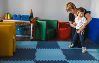A therapist supporting a young child with cerebral palsy as part of an occupational therapy session in Phnom Penh