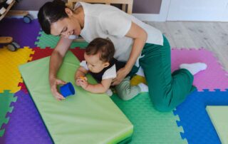 A therapist guiding a baby through a tummy time exercise to build core strength during an occupational therapy session in Phnom Penh