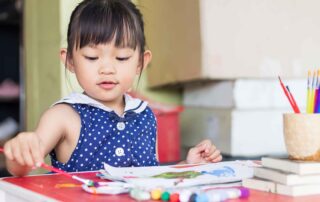 Young girl painting during an occupational therapy session in Phnom Penh, developing fine motor skills and focus through sensory play.