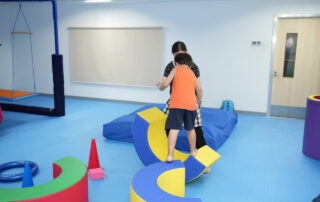 Child practicing balance with therapist in sensory gym at OrbRom Center Phnom Penh