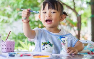 Child practicing fine motor skills with painting and craft tools during occupational therapy in Phnom Penh.